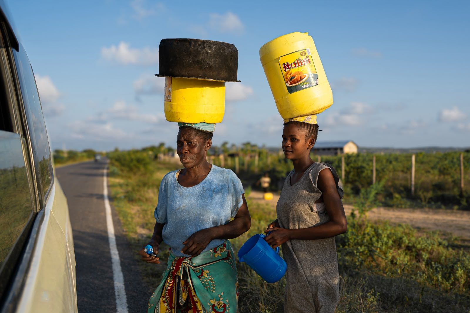 Donne che portano l'acqua in testa lungo la strada